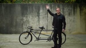 Bono and bike (source (RED) YouTube video still).JPG