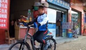 Cyclist with millstone on head video still.JPG