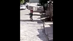Man cycling in Brazil with fridge on shoulder