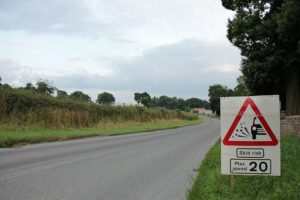 Road surface dressing loose chippings warning (licensed CC BY-2.0 by David Mitchell on Flickr).jpg