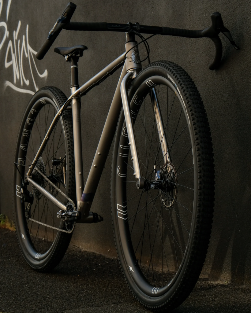 Curve Cycling Titanosaur gravel bike against black wall