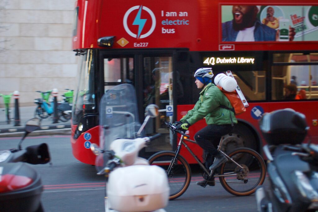 Cyclist in London with bus in background carrying luggage on back &ndash; copyright Simon MacMichael