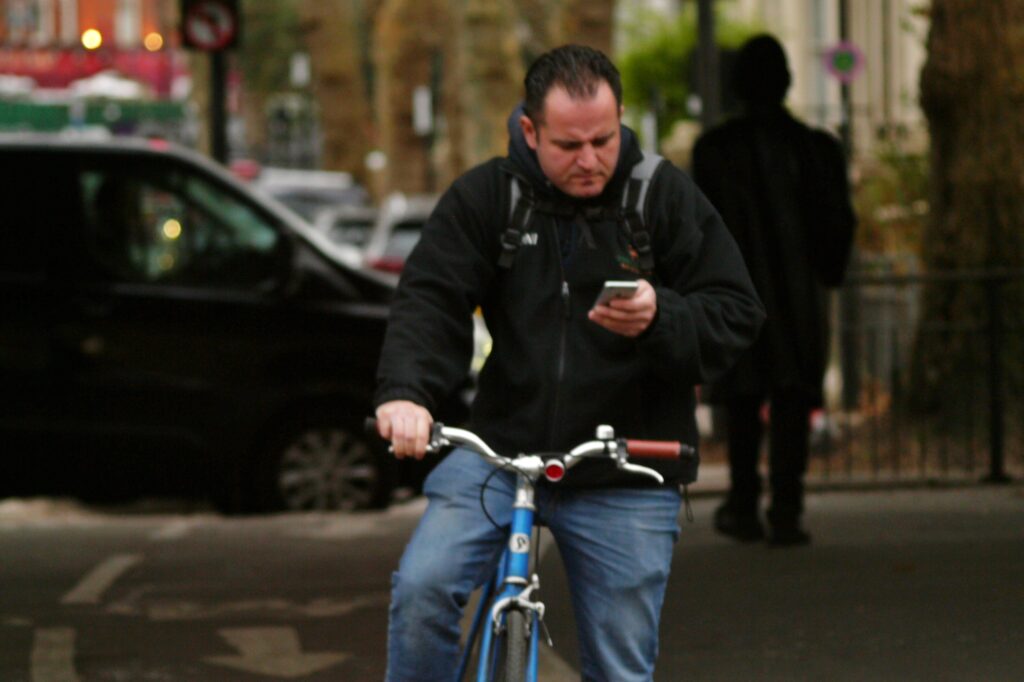 Cyclist in London on the phone – copyright Simon MacMichael