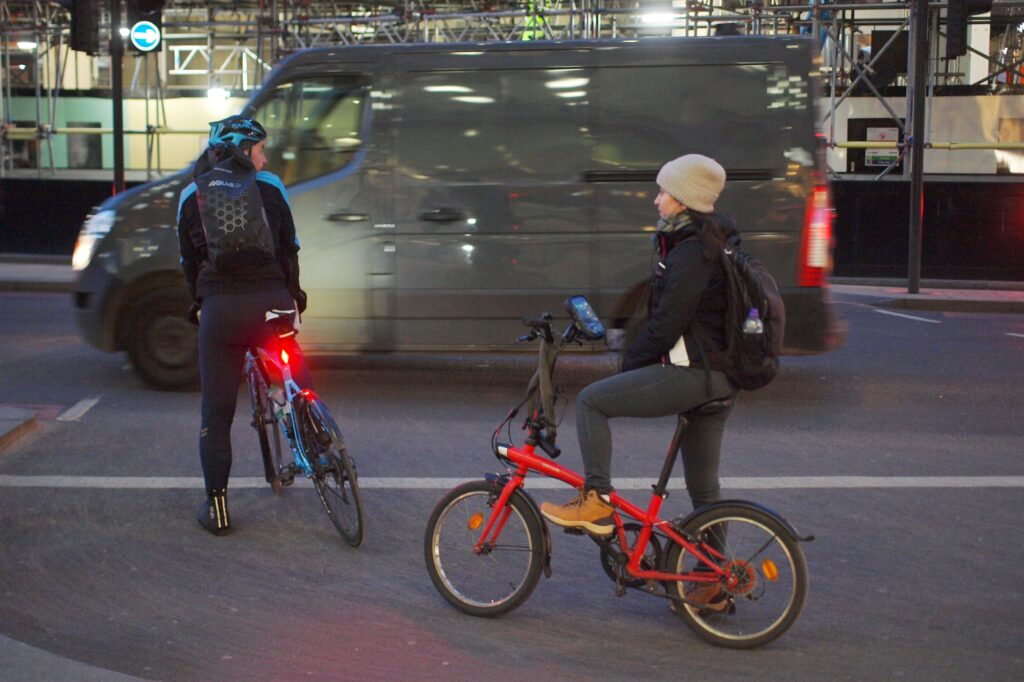 Cyclists in London folding bike and road cyclist – copyright Simon MacMichael