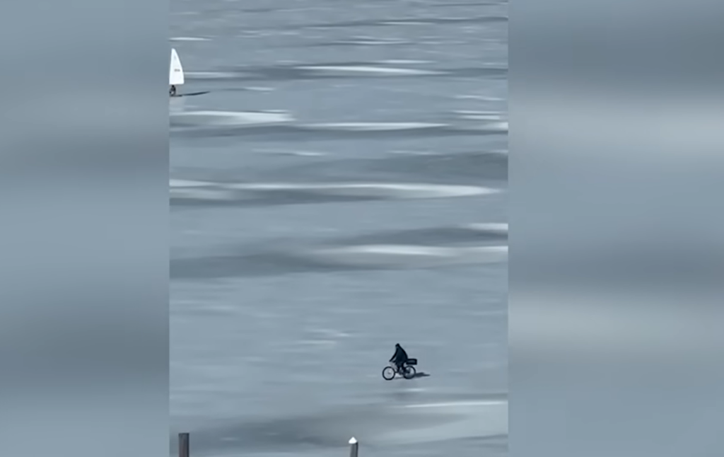 Cyclist rides bike across frozen river