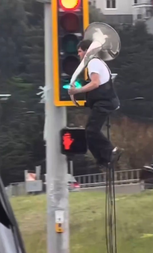 Unicyclist riding in traffic with a tuba (Image Credit: Sundance, BlueSky)