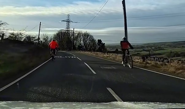 Driving instructor follows cyclist on climb