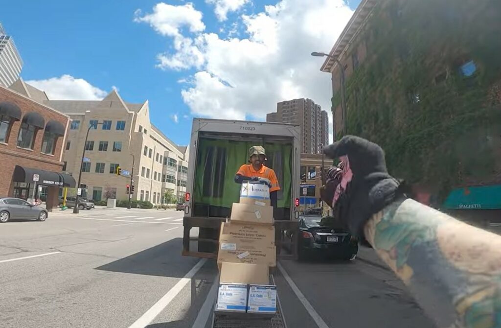 Cyclist rides up ramp of delivery lorry blocking bike lane in Minneapolis, Minnesota 2