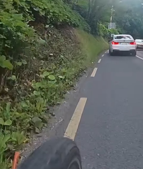 Driver overtakes cyclist on blind bend towards oncoming car