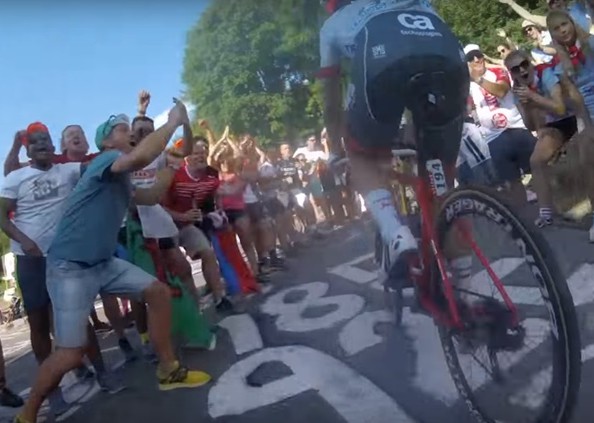 Why do fans run alongside riders on mountains at the Tour de France?