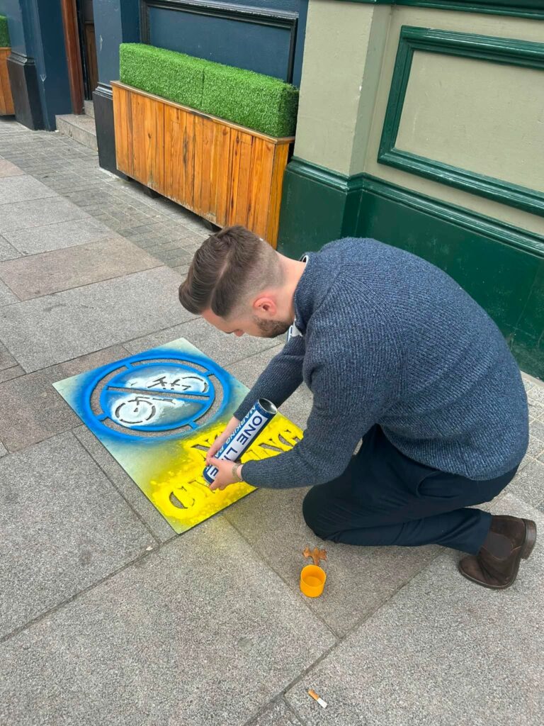 DUP councillor Kyle Moutray spraying 'no cycling' sign on pavement in Portadown