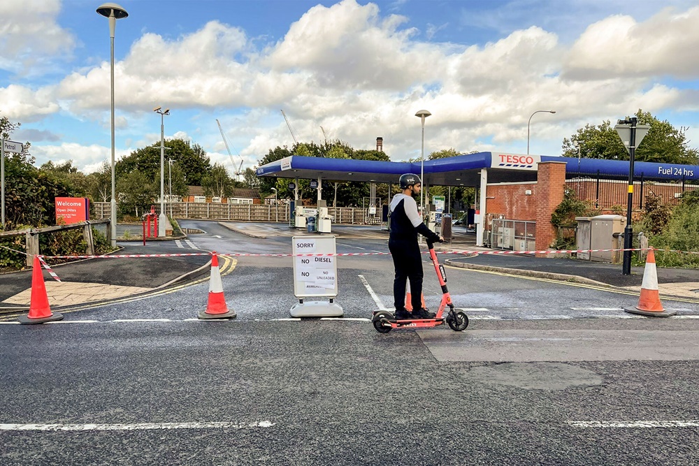 Voi e-scooter passing petrol station