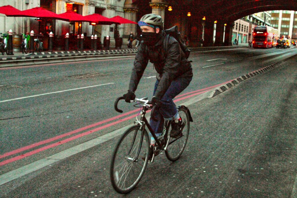 Cyclist in London with face covering in cycle lane