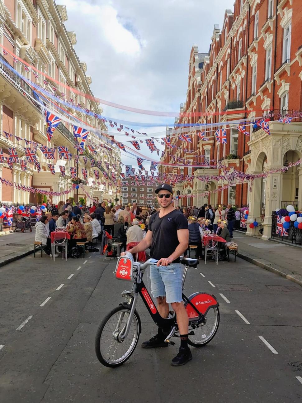 Christine&rsquo;s photograph of her partner Jeff on a Santander Cycle on the Coronation Day of His Royal Highness King Charles III as they spontaneously stumbled upon a street p