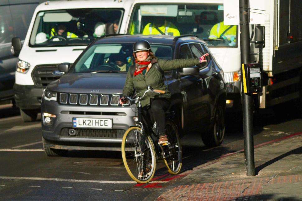 Female cyclist in London indicating in front of traffic - copyright Simon MacMichael
