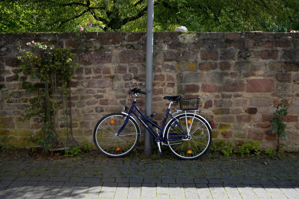 Bike leaning against pole on pavement